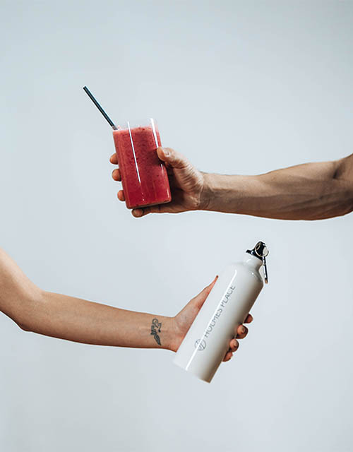 Holmes Place | χέρια που κρατάνε κόκκινο χυμό και παγούρι